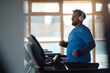 © Drazen - Happy mature athletic man running on treadmill in health club.