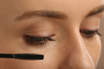 Wall Mural - Woman applying mascara onto eyelashes, closeup view