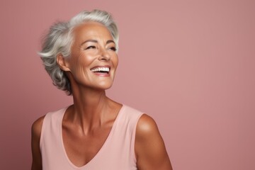 Wall Mural - Portrait of happy senior woman smiling and looking away against pink background