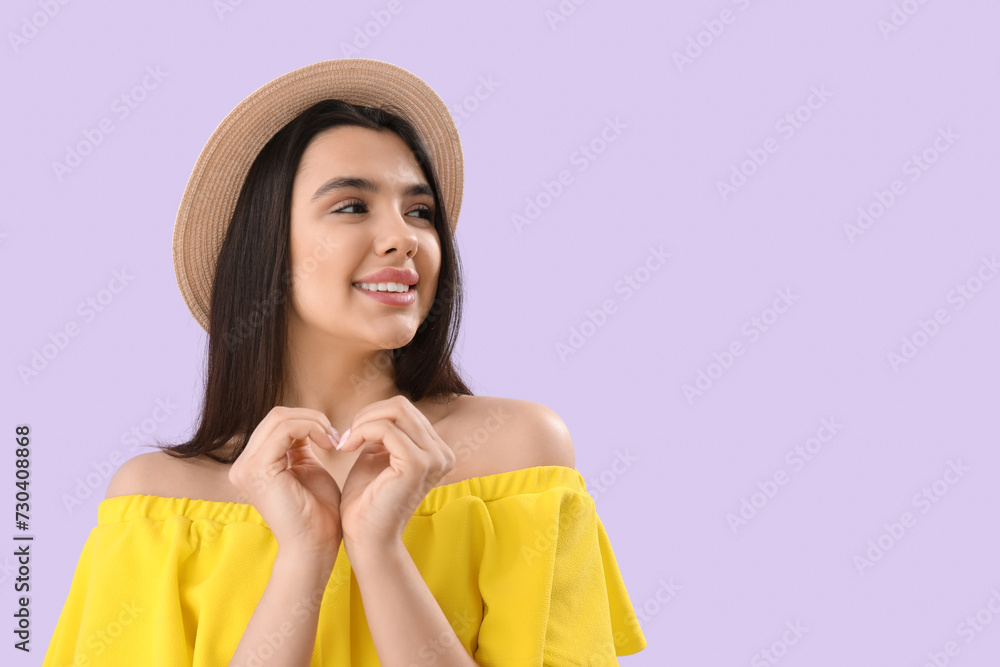 Young woman making heart with her hands on lilac background, closeup