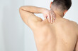 © Stefan - Rear view of a shirtless young man holding his neck in pain isolated on white background, man giving himself a massage on his neck, shirtless man touching his neck, stress, neck pain, upper back pain