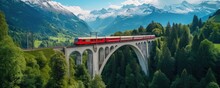 Red Train Traveling Over A Bridge In The Mountains