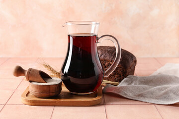 Jug of tasty kvass, yeast and bread on table