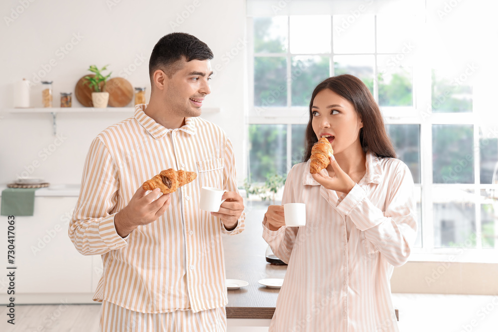 Happy young couple having breakfast in kitchen