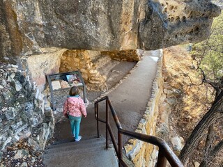 Visitors exploring the pre Colombian cave dwellings in the limestone cliffs of Walnut Canyon, used by the Sinaguan people, in Arizona, USA. 