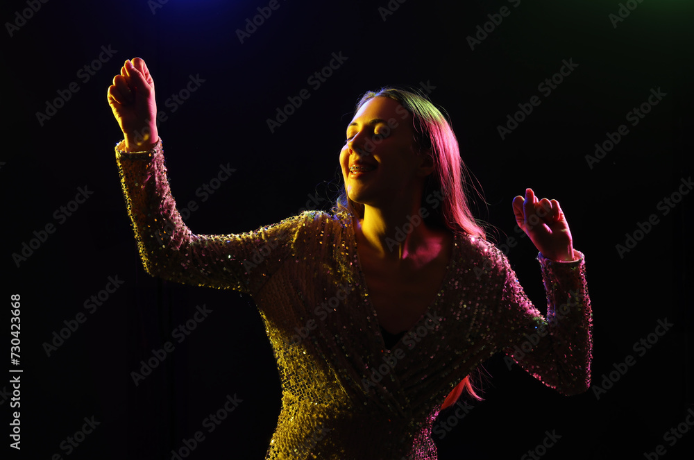 Silhouette of young woman dancing on dark background