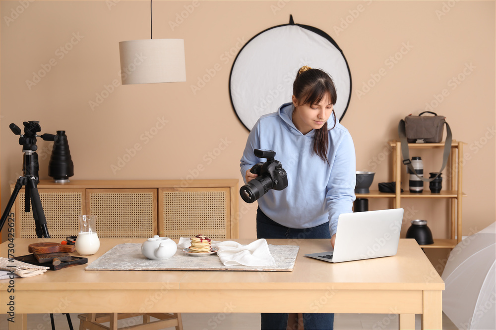 Female food photographer working with laptop in studio