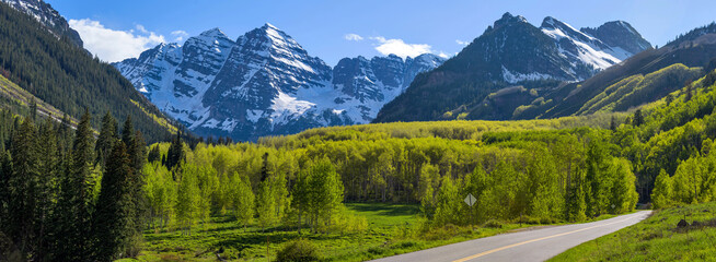 Wall Mural - Maroon Bells - A panoramic view of Maroon Bells rising high in lush green Maroon Creek Valley, as seen from side of Maroon Creek Road, on a sunny Spring evening. Aspen, Colorado, USA.