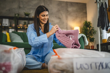 One woman caucasian adult at home choose clothes for charity donation