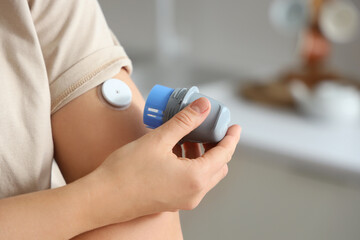 Diabetic woman with glucose sensor in kitchen, closeup