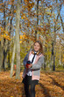 © Дмитрий Быканов - beautiful girl has fun while walking through the autumn park and fallen maple leaves. holding a glass of hot drink. the child smiles, laughs and enjoys the warmth and fresh air