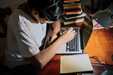 Una persona trabajando en su escritorio  con su laptop  y libros y un  café 