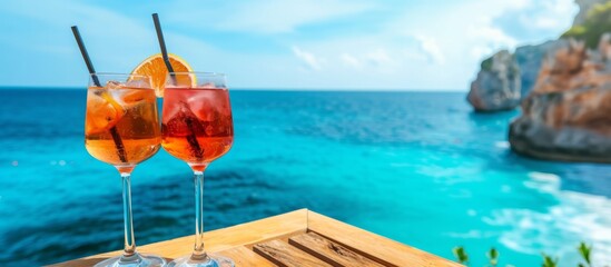 Sticker - Cocktail glasses on wooden table against a backdrop of blue sea.