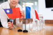 Woman secretary prepares an office for negotiations - she places flags of France and Taiwan the table