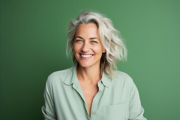 Wall Mural - Portrait of a happy senior woman smiling at camera against green background