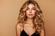 © LimeSky - Gorgeous blonde woman with elegant black dress isolated on beige background She has long curly hairstyle and emphasizes care and beauty in her hair