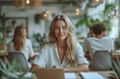 © Iona - Smiling woman working on laptop in a modern office