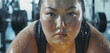 汗をかいて集中するジムでトレーニング中のぽっちゃりしたアジア人女性