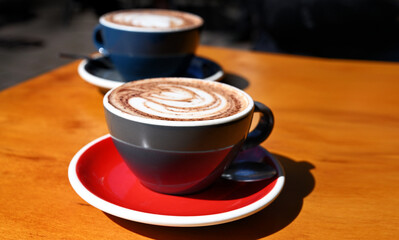 Two cappuccinos drinks on a wooden table