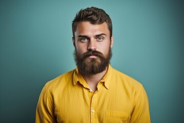 A photo of a man with a beard confidently wearing a bright yellow shirt.