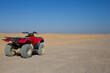 © malazoniia - Red quad bike in the Arabian desert standing on safari road. Concept of active extreme sports in the sandy desert on sunny day