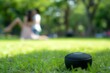 speaker on grass with blurry couple swaying gently at a park