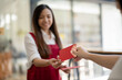© Wasana - A smiling woman hands out a traditional red envelope, known as 'Ang Pao', as part of the Chinese New Year festivities..