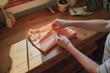 person folding peach fuzz color shorts on a wooden desk