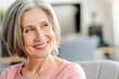 © Maria Vitkovska - Closeup portrait smiling confident senior woman sitting on comfortable sofa at home. Happy retired female with stylish gray hair, white teeth looking away. Natural beauty, healthy lifestyle concept