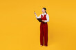 Full body young employee business woman of Asian ethnicity wears red vest shirt work at office hold clipboard paper account documents point aside isolated on plain yellow background. Career concept.