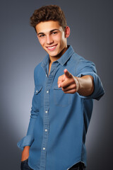 Friendly young male in casual attire pointing towards the camera, engaging directly with the audience