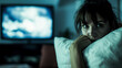 © XaMaps - A concerned woman tightly holding a pillow, with a blurred image of a storm on the TV behind her