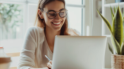 Wall Mural - A woman sitting at a table, focused on her laptop computer.