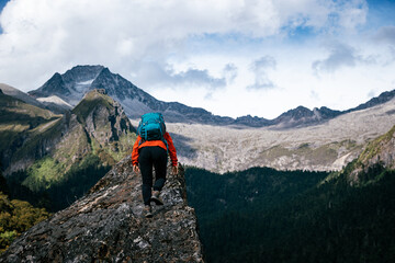 Wall Mural - Woman hiker climbing to mountain top in tibet