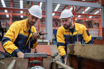 Wall Mural - Industrial engineer in safety helmet uniform jacket working in heavy steel engineering factory. Technician manager, Latin worker examining machine maintenance in metalwork product facility workplace