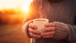 Warm sunrise hue on a person in a cozy sweater holding a steaming mug, breath visible in the crisp air