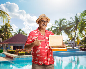 Poster - Mature tourist holding a box of cigars by a swimming pool