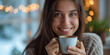 Beautiful woman smiling and hold a mug of hot drink coffee or tea with morning light cozy feeling on a winterday bokeh