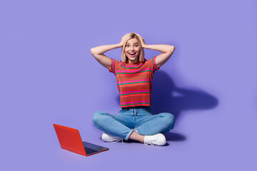 Full body photo of surprised funny programmer young girl hands head watching online casino in laptop isolated on violet color background