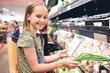© Ievgen Skrypko - Pretty girl child buying green onion with shopping list in supermarket. Beautiful female preteen kid choosing vegetables in grocery store