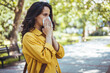 © Dragana Gordic - Portrait of unhealthy cute  female in yellow top with napkin blowing nose, looks to the source of the allergy, place for advertising. Rhinitis, cold, allergy concept. Pollen allergy symptoms