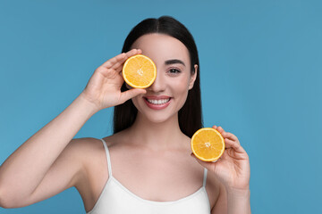 Poster - Beautiful young woman with pieces of orange on light blue background