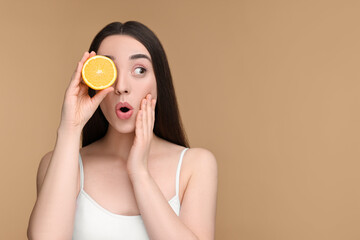 Wall Mural - Emotional young woman with piece of orange on beige background. Space for text