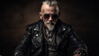 Old man punk rocker with shaved with spiky gray hair in a mohawk, beard and mustache, sunglasses and black leather jacket with chains sitting on a motorcycle in a dark studio setting. Criminal guy