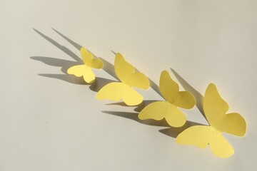 Wall Mural - Yellow paper butterflies on light grey background, top view