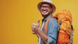 © ORG - A young man smiles happily with a thumbs up and a large backpack on, ready to leave on a blue background.