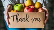 © Ilja - Grateful volunteers holding thank you sign over food donation box with groceries