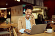 © bnenin - An African female manager, sitting at the restaurant, making a phone call while working over the laptop.