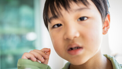 Asian boy holding up his first baby tooth that fell out. Selective Focus.