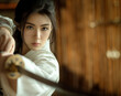 © J S - Asian Japanese combat or ninja girl wearing white gi and holding a sword, copy space in background